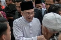 Anwar menyantuni jemaah selepas menunaikan solat Jumaat di Masjid Usamah Bin Zaid. Foto: Bernama 