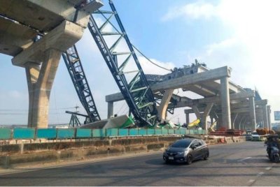 Kereta-kereta melintas di sebelah kren yang runtuh dan meranapkan dua kenderaan semasa pembinaan lebuh raya bertingkat di wilayah Samut Sakhon, Thailand. - Foto: Agensi