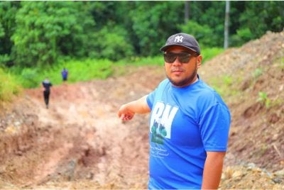 Mohd Naim menunjukkan keadaan jalan ke Kampung Karamuak yang masih bertanah merah.