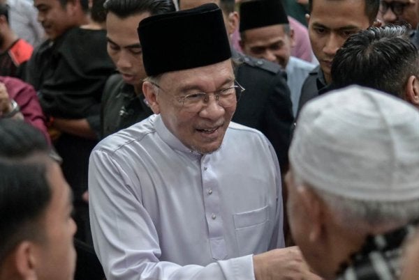 Anwar menyantuni jemaah selepas menunaikan solat Jumaat di Masjid Usamah Bin Zaid. Foto: Bernama 