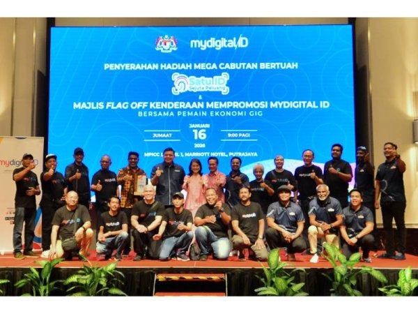 Rita Irina (berdiri, tujuh dari kiri) bergambar bersama pemain ekonomi GIG pada Majlis Flag Off Kenderaan Mempromosi MyDigital ID bersama Pemain Ekonomi GIG di Putrajaya, pada Jumaat. / Foto: ASRIL ASWANDI SHUKOR