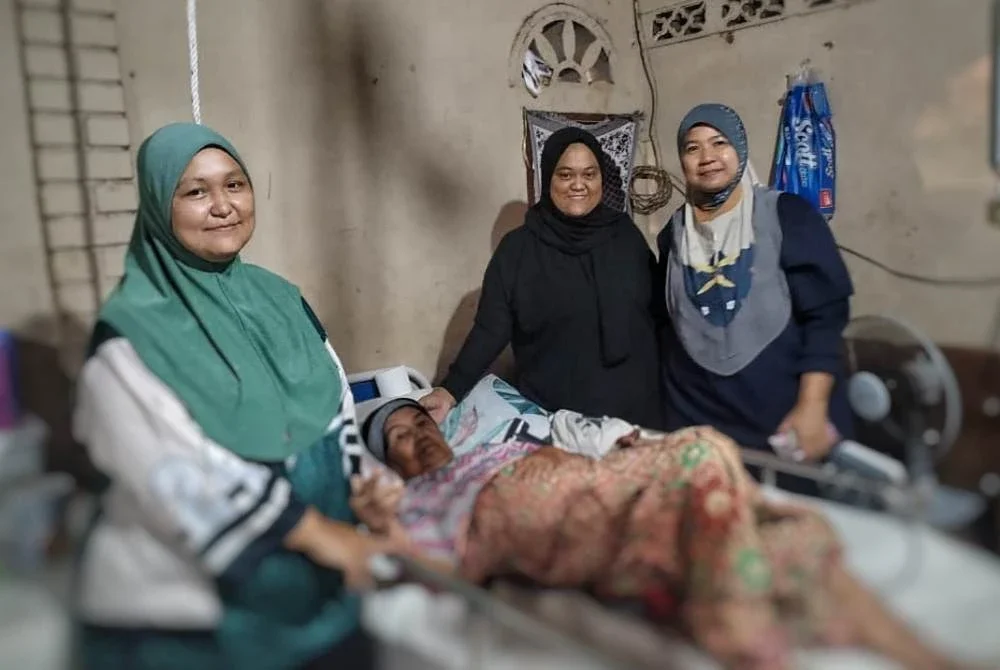 Nur Nurliana (tengah) bersama dua kakaknya menjaga Noriah yang menderita penyakit angin ahmar di Felda Kota Gelanggi Dua, di sini.