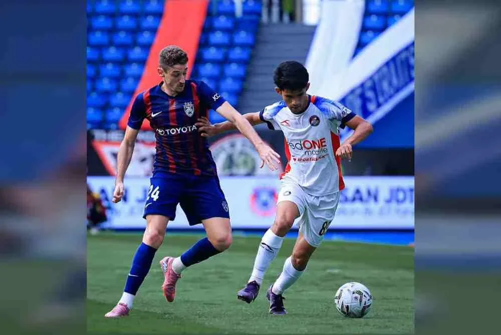 Pemain PDRM FC, Muhammad Fakhrul Azim Mohd Zulphatah cuba mengawal pergerakan pemain JDT, Oscar Aribas pada perlawanan berkenaan. - Foto Johor Southern Tigers