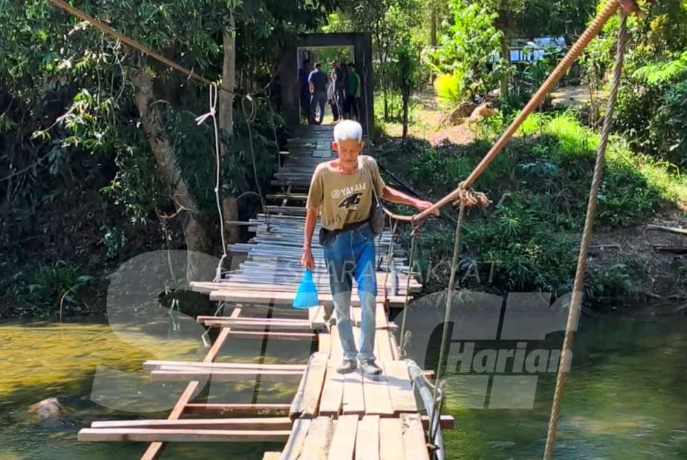Azmi terpaksa berjalan kaki setiap kali menyeberangi titi gantung dan meninggalkan motosikalnya di seberang berhampiran kebun.