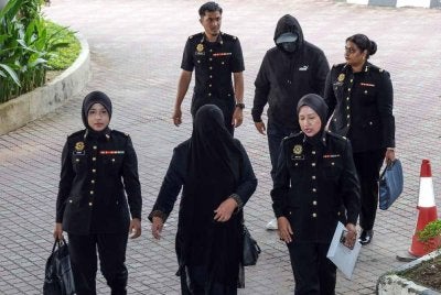  Pegawai Imigresen Gred KP22, Mohamad Fadzli Abdul Rahim, 46, dan isterinya, Suhana Ismail, 45, diiringi pegawai Suruhanjaya Pencegahan Rasuah Malaysia (SPRM) ketika dibawa ke Mahkamah Sesyen Shah Alam hari ini bagi menghadapi pertuduhan rasuah dan pengubahan wang haram. Foto Bernama 