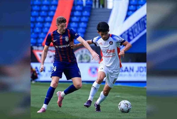 Pemain PDRM FC, Muhammad Fakhrul Azim Mohd Zulphatah cuba mengawal pergerakan pemain JDT, Oscar Aribas pada perlawanan berkenaan. - Foto Johor Southern Tigers