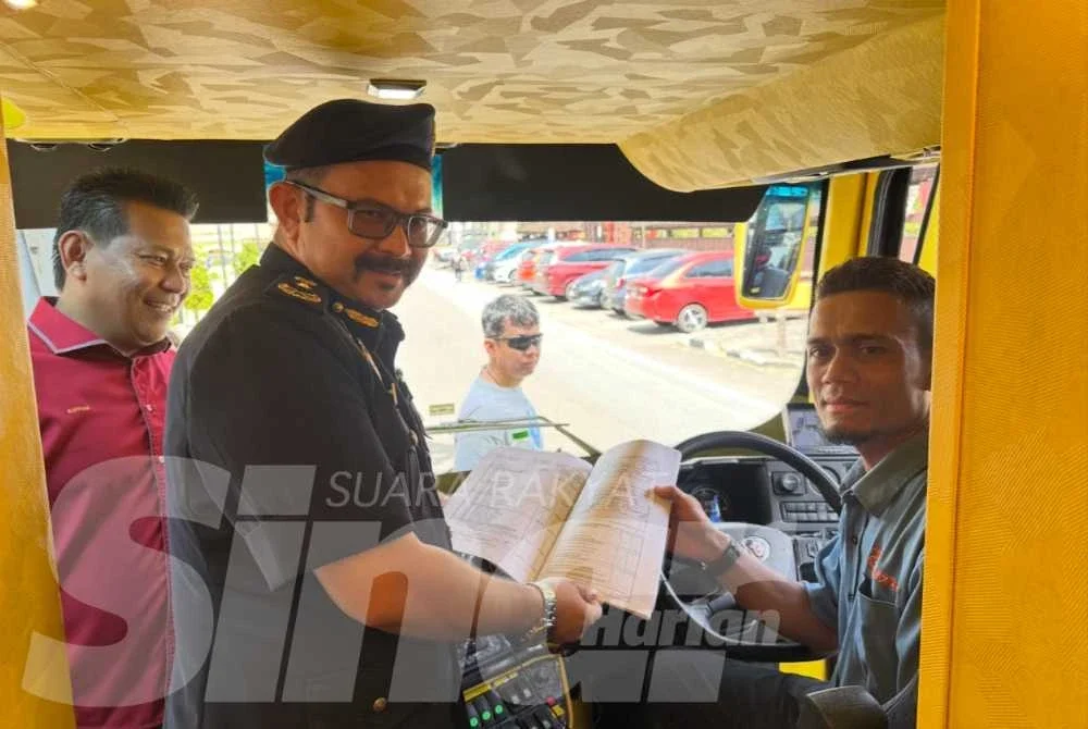 Mohd Misuari (tengah) melihat buku catatan pemandu bas.