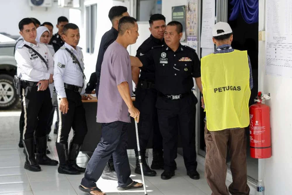 Anggota polis, Zainudin Nudong tiba menggunakan tongkat menunaikan tanggungjawab mengundi pada hari pengundian awal sempena Pilihan Raya Kecil (PRK) Parlimen Kinabatangan dan Dewan Undangan Negeri (DUN) Lamag di Teratak Ibu Pejabat Polis Daerah Kinabatangan. Foto Bernama