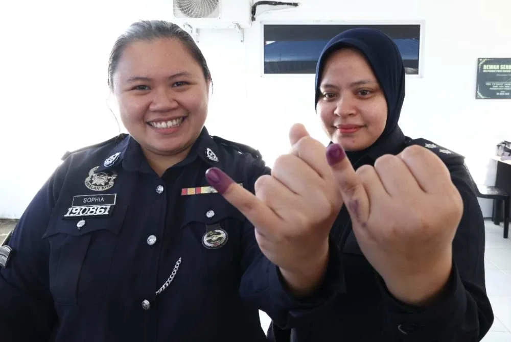 Sophia Lim (kiri) dan Siti Hajar menunjukkan jari yang dicelup dakwat selepas mengundi pada proses pengundian awal bagi PRK Parlimen Kinabatangan dan DUN Lamag di Teratak Ibu Pejabat Polis Daerah Kinabatangan. Foto Bernama
