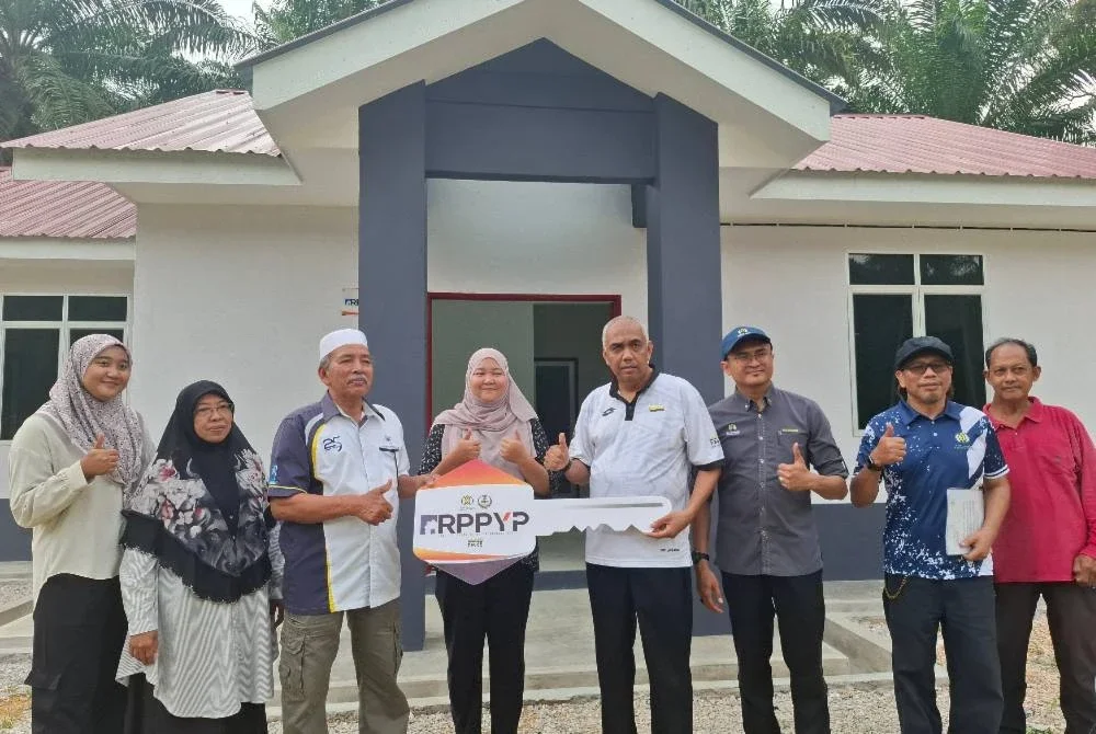 Khairudin (empat dari kanan) menyerahkan replika kunci kepada penerima Rumah Perakku Prihatin Yayasan Perak (RPPYP), Zaid Abu Hassan Shaari yang diwakili isterinya, Syarifah Ruwaida Syed Ise, 27, di Kampung Selat, Layang-Layang Kiri, Parit pada Selasa.