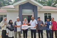 Khairudin (empat dari kanan) menyerahkan replika kunci kepada penerima Rumah Perakku Prihatin Yayasan Perak (RPPYP), Zaid Abu Hassan Shaari yang diwakili isterinya, Syarifah Ruwaida Syed Ise, 27, di Kampung Selat, Layang-Layang Kiri, Parit pada Selasa.