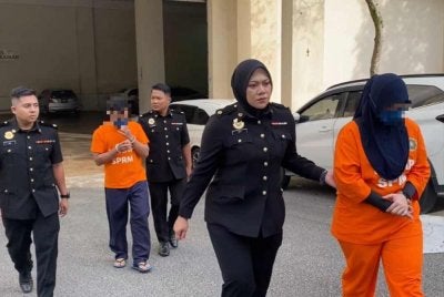 Kedua-dua suspek diiringi pegawai SPRM ketika di bawa ke mahkamah untuk perintah reman pada Selasa. Foto SPRM Pahang