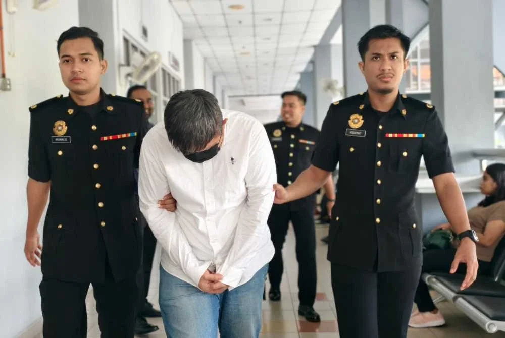 Tertuduh ketika dibawa pegawai SPRM ke Mahkamah Sesyen Seremban pada Jumaat.