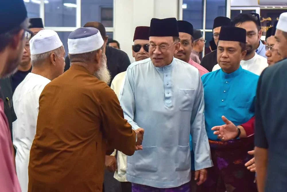 Anwar menyantuni jemaah sebelum menunaikan solat Jumaat di Surau al-Amin. Foto Bernama