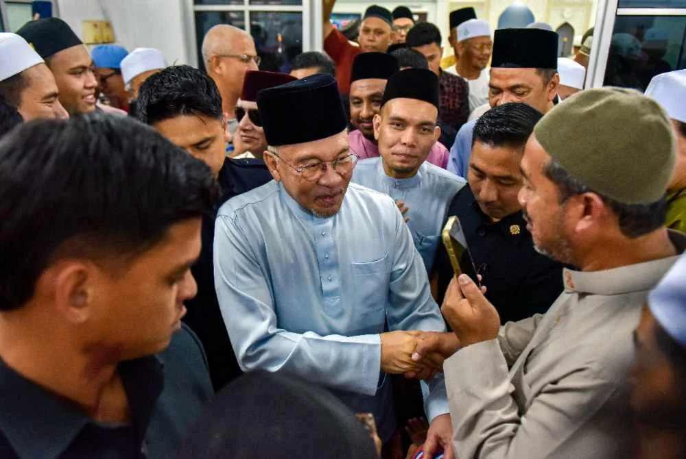 Anwar menyantuni jemaah selepas menunaikan solat Jumaat di Surau al-Amin. Foto Bernama