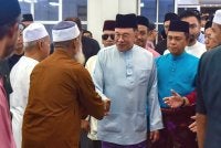 Anwar menyantuni jemaah sebelum menunaikan solat Jumaat di Surau al-Amin. Foto Bernama