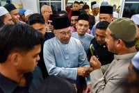 Anwar menyantuni jemaah selepas menunaikan solat Jumaat di Surau al-Amin. Foto Bernama