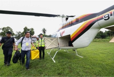 Petugas Suruhanjaya Pilihan Raya membawa peti undi untuk dihantar ke Pusat Mengundi di Kuamut menggunakan helikopter di padang Majlis Daerah Kinabatangan. Foto Bernama