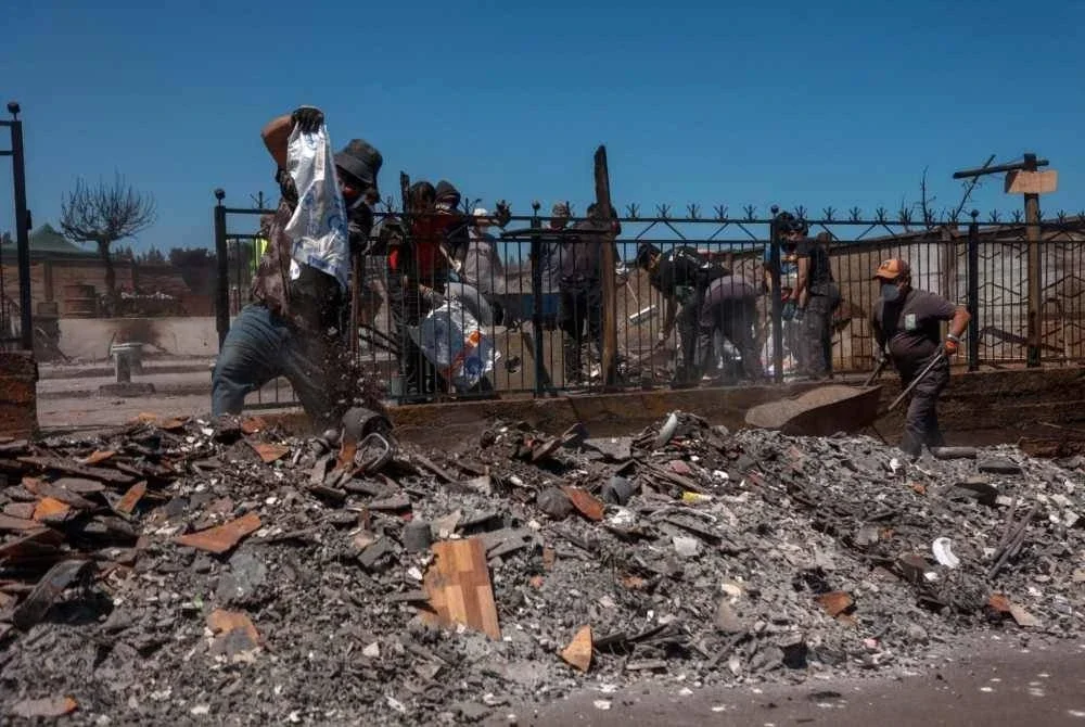 Penduduk bergotong-royong membersihkan kawasan kejiranan mereka selepas kebakaran reda.
