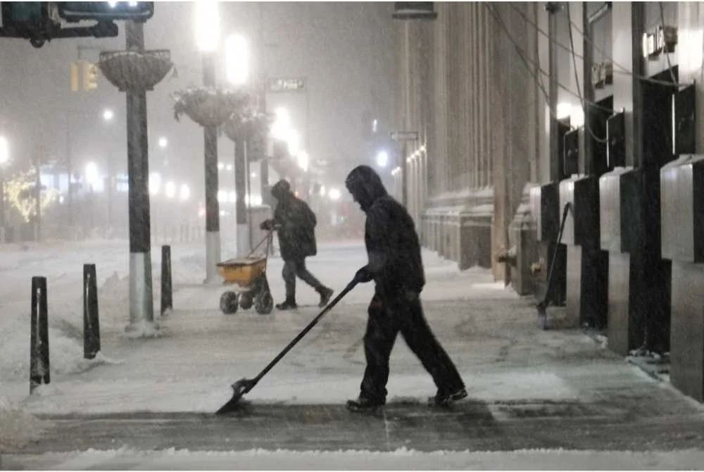 Orang ramai membersihkan salji di Lower Manhattan ketika ribut musim sejuk melanda New York City, menyebabkan suhu beku dan angin kencang. - AFP