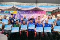 Aaron (berdiri, tengah) bersama penerima sempena Majlis Penyerahan Mock Cheque Peruntukan Program Satelit Komuniti Rakyat Madani Tahun 2026 Peringkat Ipoh di Pusat Nadi Kampung Dato’ Ahmad Said Tambahan 2, pada Sabtu.