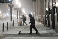 Orang ramai membersihkan salji di Lower Manhattan ketika ribut musim sejuk melanda New York City, menyebabkan suhu beku dan angin kencang. - AFP