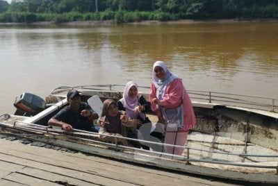 Siti Zamziah (kanan) bersama ibu dan adiknya selesai membuang undi dan bersedia untuk pulang menaiki bot ke Kampung Bilit Seberang, Sukau.