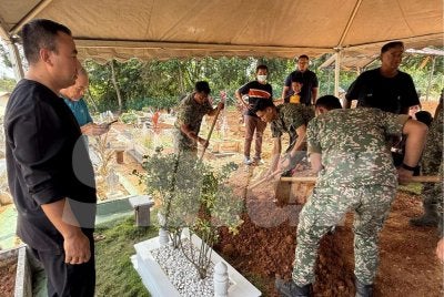 Mohd Fikry (kiri) di samping pusara dua anaknya Al Fateh dan Maryam Al Khawla.