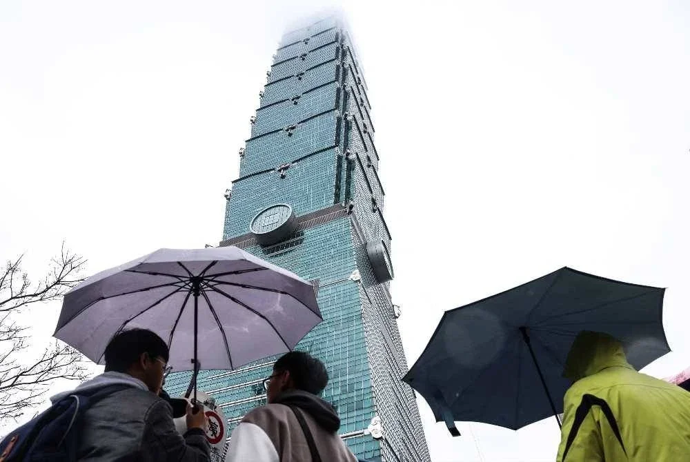 Orang ramai memegang payung di bawah bangunan ikonik Taipei 101 bagi menyaksikan pendakian Honnold.-AFP