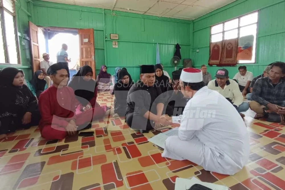 Mohamad Faizu (kanan) menikahkan tiga pasangan pengantin di Surau An-Nur, Kampung Sungai Pergam sebelum diraikan di Dewan Orang Ramai kampung berkenaan.