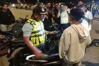 Mohd Zamzuri mendekati salah seorang penunggang motosikal yang ditahan dalam operasi yang dijalankan.
