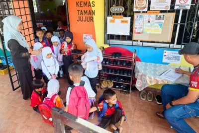 Siti Sarah Shammimie melihat murid-murid Tabika Kemas Taman Jujur memakai kasut untuk pulang.