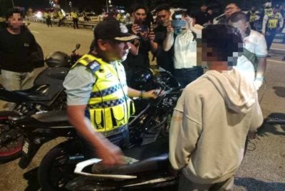 Mohd Zamzuri mendekati salah seorang penunggang motosikal yang ditahan dalam operasi yang dijalankan.