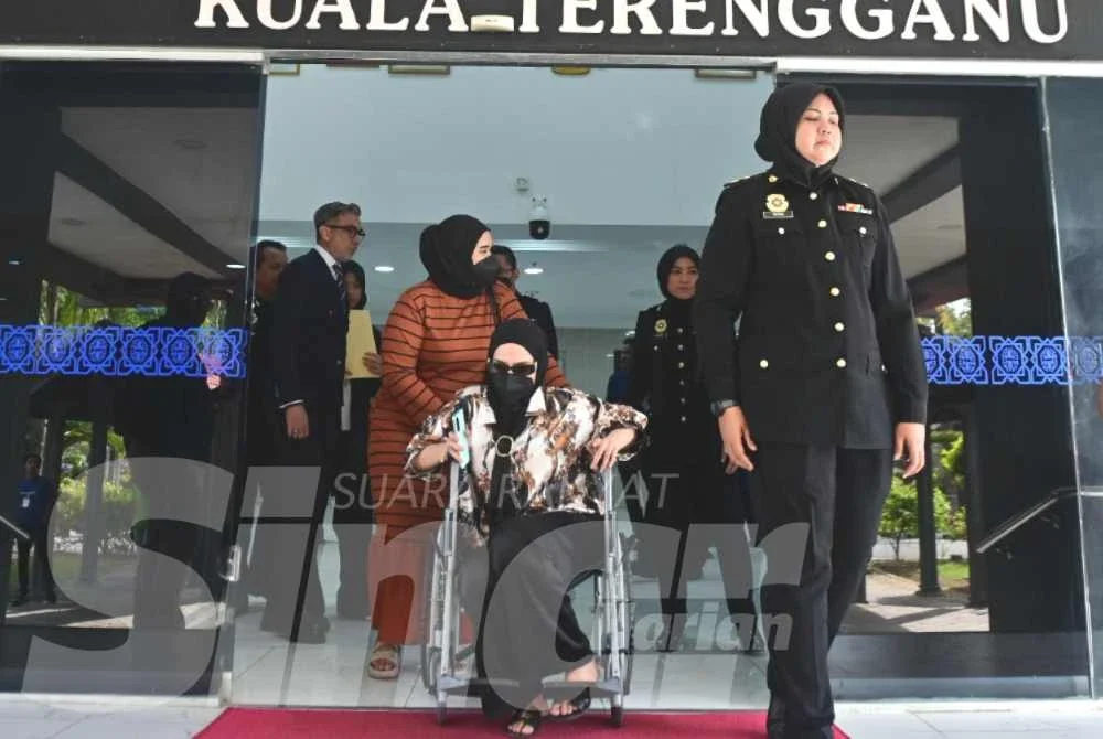 Tertuduh berkerusi roda sebelum bangun dan dipimpim menuruni tangga mahkamah di Kuala Terengganu.