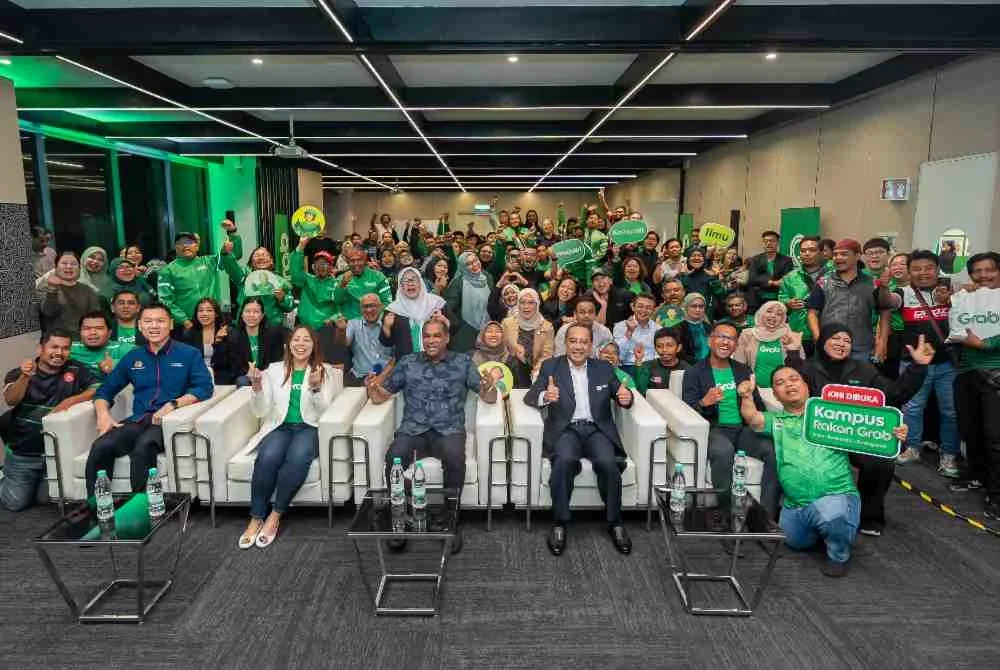 Adelene (duduk, dua dari kiri) dan Ramanan (duduk, tengah) bergambar bersama rakan penunggang dan pemandu Grab yang hadir pada majlis pelancaran Kampus Rakan Grab pada Isnin.