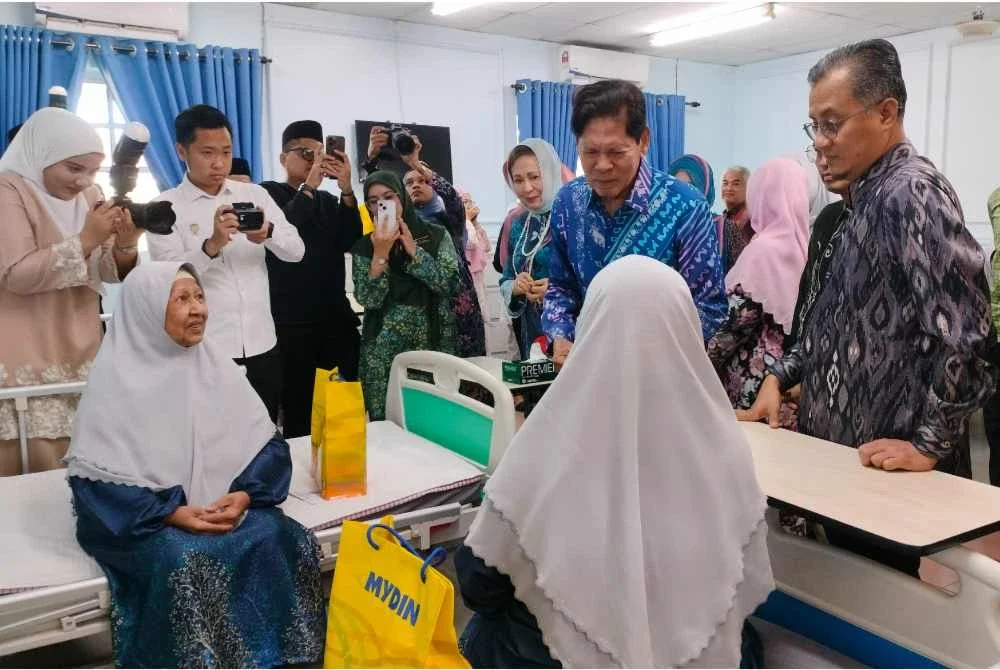 Mohamad (kanan) mengiringi Ramli menziarahi penghuni Pusat Jagaan Warga Emas Darul Hanan.