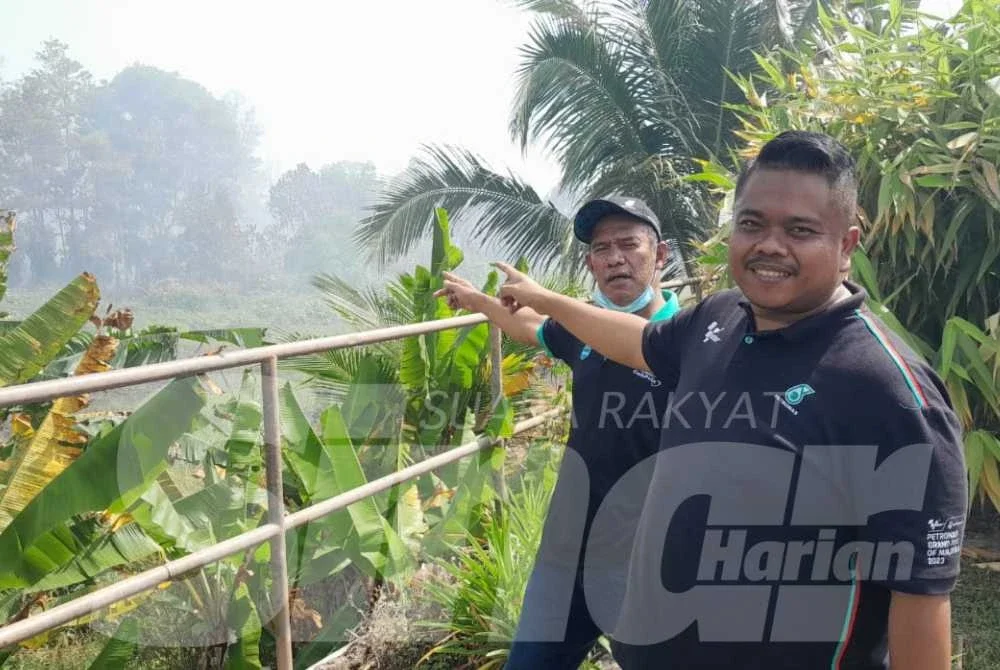 Suhaimi (kiri) menunjukkan lokasi kebakaran tanah gambut di Taman Bayu Damai, Pengerang sehingga penduduk terpaksa dipindahkan ke pusat transit sementara.