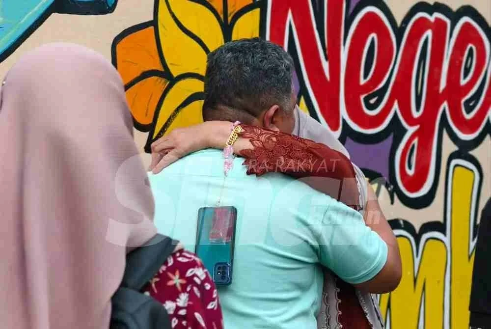 Ahli keluarga mangsa yang berpelukan tidak dapat menahan kesedihan