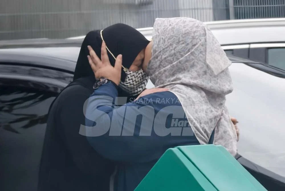 Kelihatan dua wanita saling berpelukan.