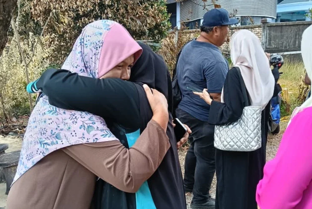 Norhaeda (kiri) tidak dapat menahan sebak apabila menerima kunjungan daripada Yusnita serta rombongan Yadim Kelantan di tapak rumahnya yang terbakar di Jalan Tok Guru, Kota Bharu pada Rabu. Foto: Yadim