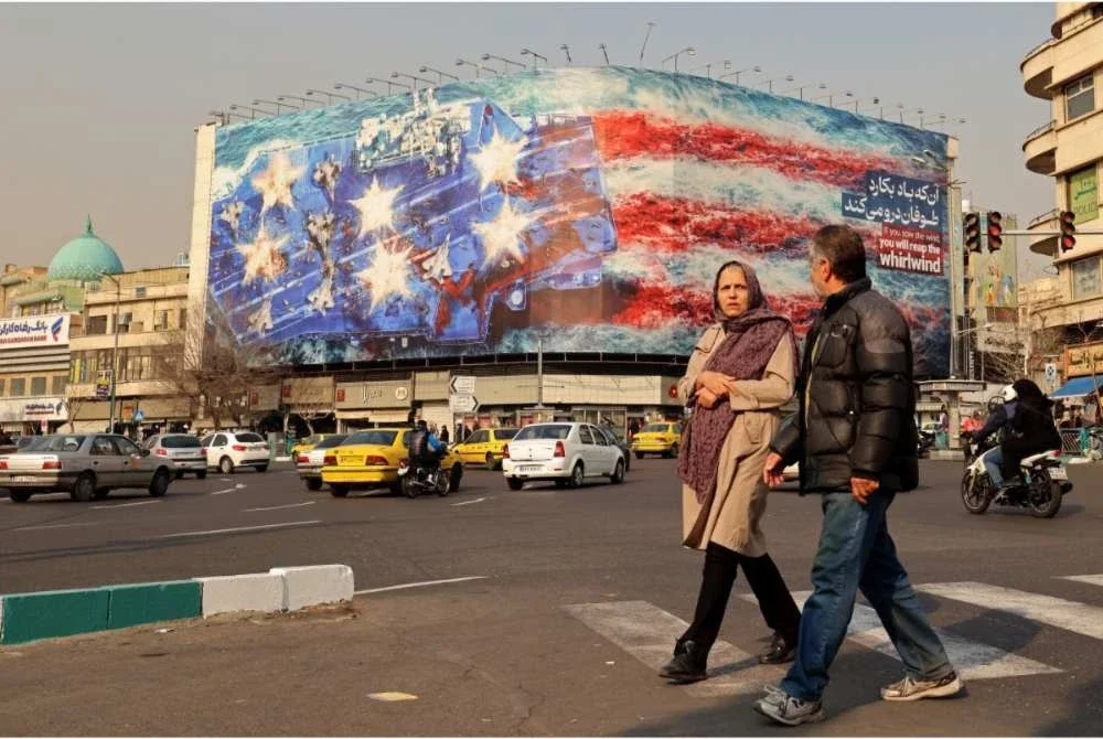 Orang ramai berjalan melepasi papan iklan anti-Amerika Syarikat di Dataran Enqelab, Teheran. - AFP