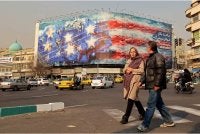 Orang ramai berjalan melepasi papan iklan anti-Amerika Syarikat di Dataran Enqelab, Teheran. - AFP