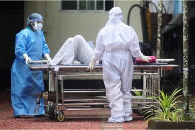Petugas kesihatan memakai pakaian pelindung semasa mengendali seorang pesakit disyaki dijangkiti virus Nipah di hospital kerajaan di Kozhikode, Kerala. - AFP