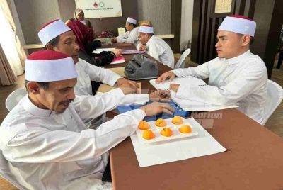 Eiman Najwan (kanan) mengajar dua orang dewasa di pusat pengajian al-Quran di Bunut Payong. Foto: SINAR HARIAN/ADILA SHARINNI WAHID