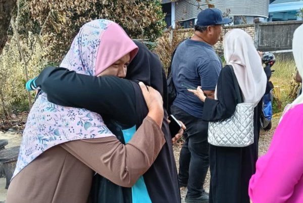 Norhaeda (kiri) tidak dapat menahan sebak apabila menerima kunjungan daripada Yusnita serta rombongan Yadim Kelantan di tapak rumahnya yang terbakar di Jalan Tok Guru, Kota Bharu pada Rabu. Foto: Yadim