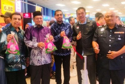 Azmin (tengah) menunjukkan ayam yang ditawarkan pada harga promosi sempena pembukaan Mydin Gurun.
