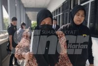 Hamiza (kiri) dibawa pegawai SPRM ke mahkamah pada Jumaat.