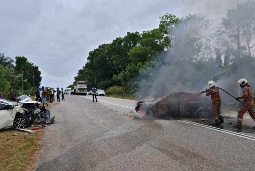 Anggota bomba memadamkan kebakaran kereta Persona selepas terlibat dalam kemalangan empat kenderaan di Kilometer 43, sempadan Mersing. - Foto JBPM Johor