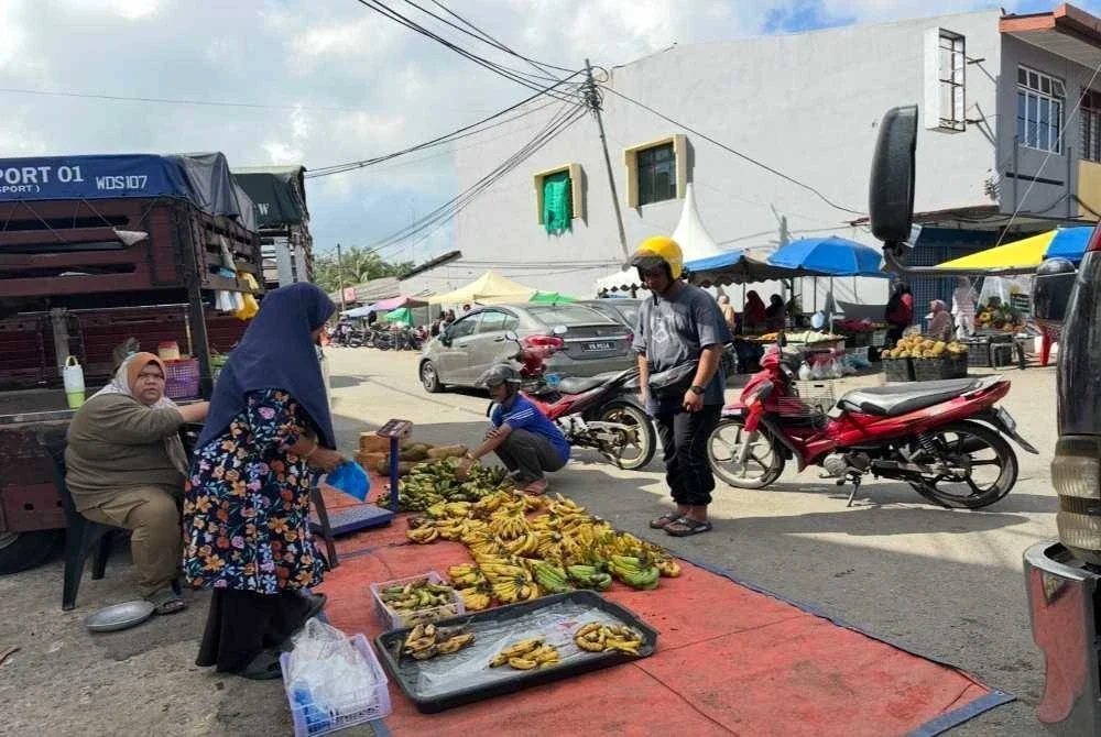 Peniaga yang sibuk melayani pelanggan di Pasar Jelawat. 