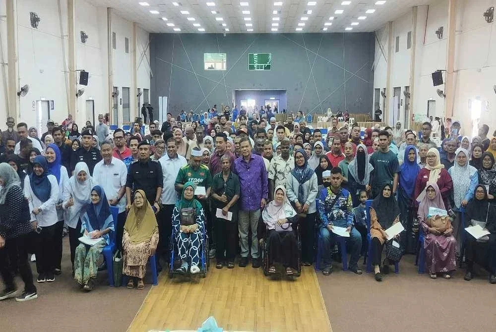 Saifuddin Nasution (tengah) bersama penerima bantuan wang ihsan fasa 2 di Kompleks Sukan Kulim Hi-Tech Park pada Sabtu. 